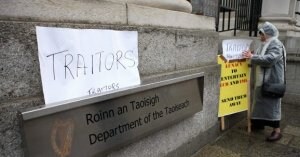 Una señora coloca carteles con la palabra 'traidores', ayer, en las puertas de la sede del primer ministro irlandés. ::                             AFP