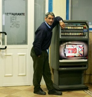 Un hombre se fuma un cigarrillo, apoyado en una máquina expendedora. ::                             AFP