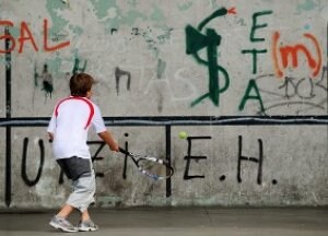 Un chaval juega a frontenis entre pintadas en un pueblo vasco. ::                             AFP