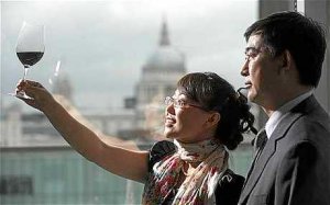 La dueña de la bodega Zhang Jing y el enólogo Li Demei observan una copa del vino ganador.