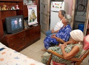 Tres mujeres católicas observan en la televisión la intervención del viernes del arzobispo de Santiago de Cuba, Dionisio García Ibáñez. / EFE