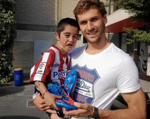 Unax posa feliz en brazos de Llorente con el par de botas de fútbol que le regaló el rojiblanco. /E. C.