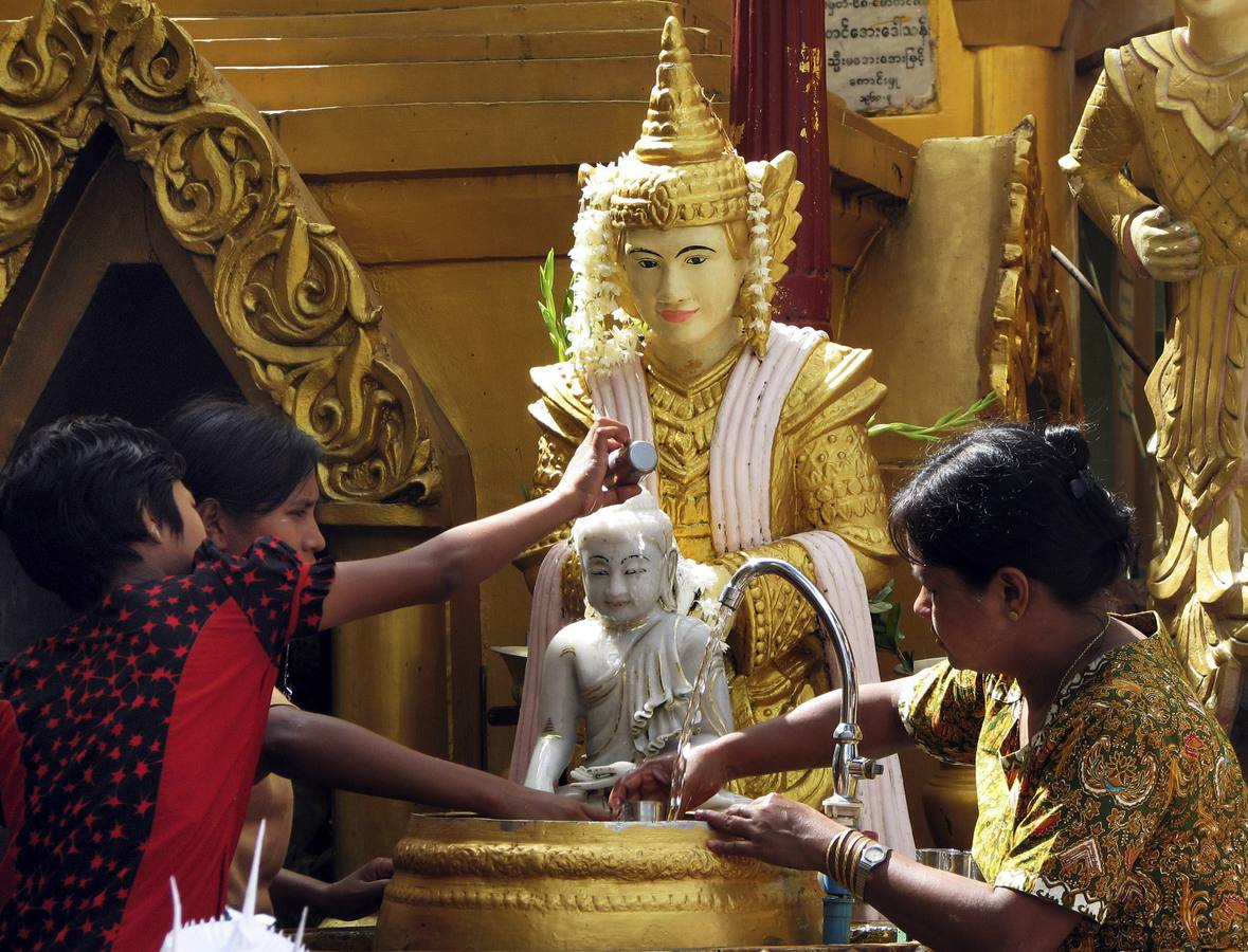 Devotos colocando cuencos de agua junto a imagen de Buda