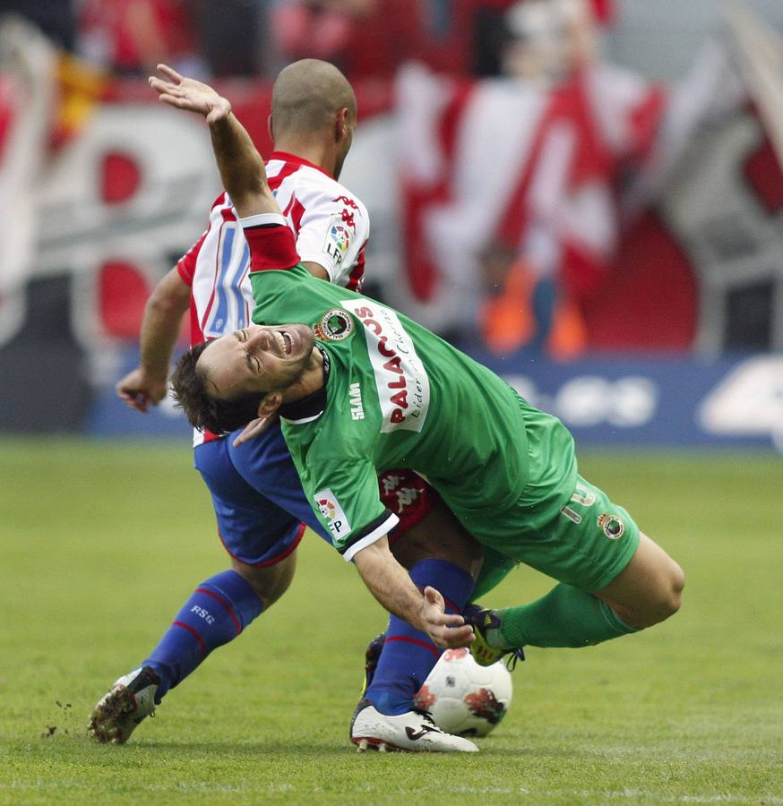 El centrocampista del Sporting de Gijón Alberto Lora pelea un balón con el delantero del Racing de Santander Pedro Munitis