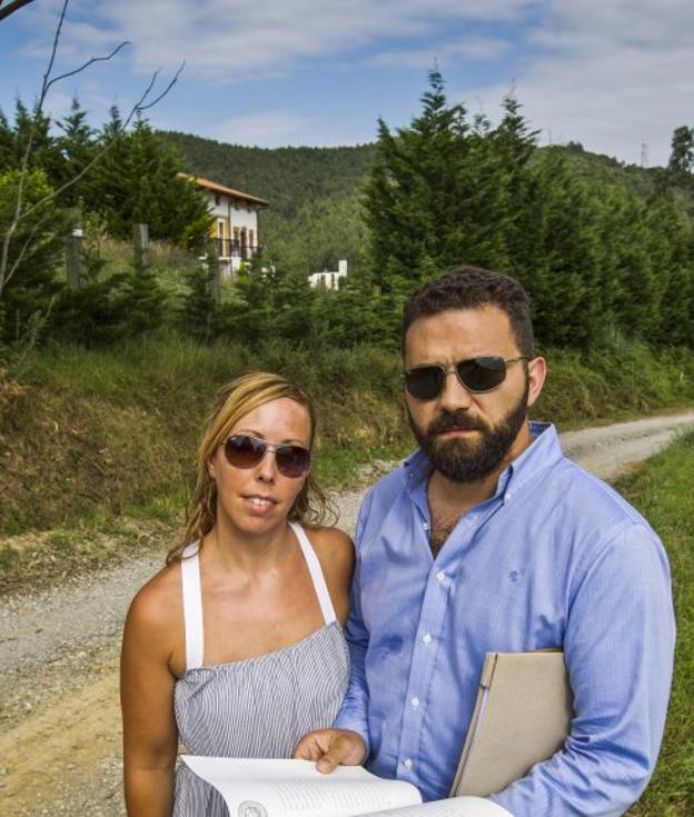 Lidia y Alfonso, ante la vivienda (al fondo) que adquirieron y no pueden disfrutar en Anero.