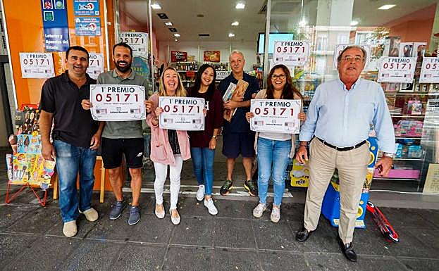 Responsables de lotería, propietarios, trabajadores y amigos muestran felices el número premiado. 