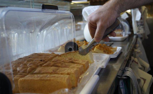 Un dependiente coge un trozo de bizcocho para despachar.