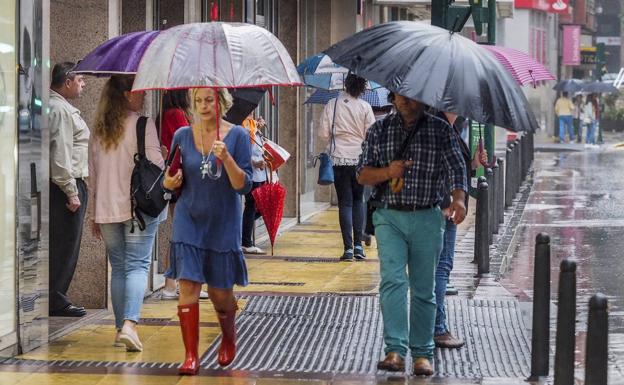 Imagen principal - Gente bajo la lluvia, este miércoles en Torrelavega