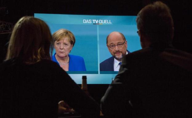 Dos periodistas siguen en un monitor el debate entre Merkel y Schulz.