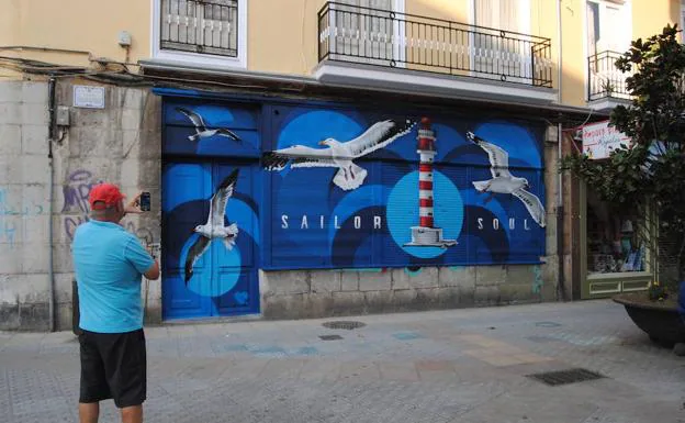Los vecinos se paran a contemplar y a fotografiar el grafiti que ha pintado Joel Arroyo en un bajo de la calle Calvo Sotelo.