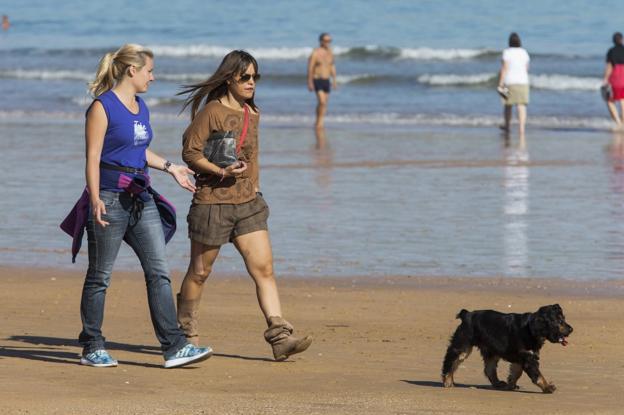 Dos mujeres paseaban ayer con un perro por una de las playas de Santander. 