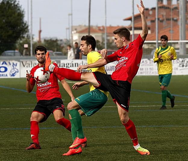 Cano (izquierda) y Mier, del Laredo, luchan por el balón con Riky, del Tropezón. 