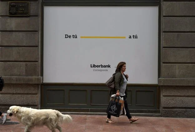 Una mujer pasa por delante de una oficina de Liberbank. :: 