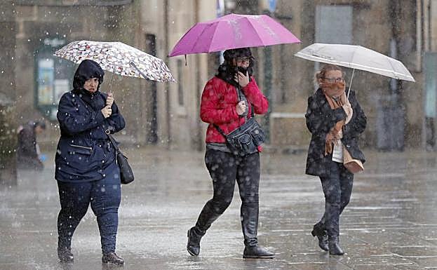 El temporal ha azotado especialmente a Galicia. En la imagen, tres personas se protegen del agua en Santiago de Compostela.