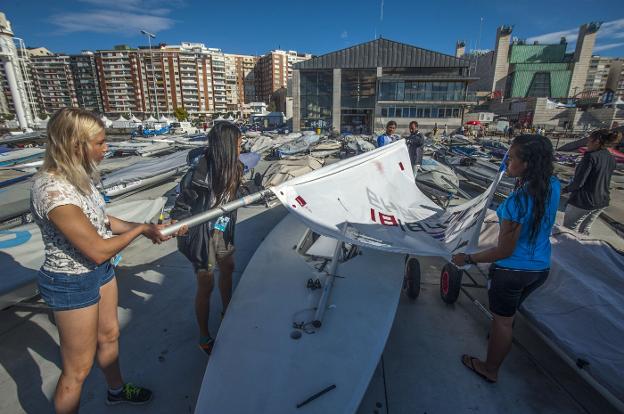  De Madrid a Santander. Tres regatistas trabajan en un barco de la clase Láser en el Mundial de Santander 2014 en la explanada del CEAR, el edificio que servirá también como sede de la Federación Española de Vela. 