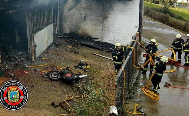 Los bomberos trabajan fuera del garaje.