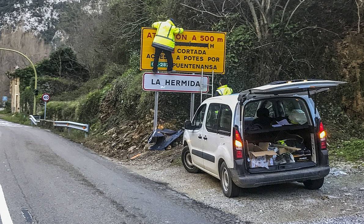 Un operario coloca el cartel que anuncia el corte de la carretera.