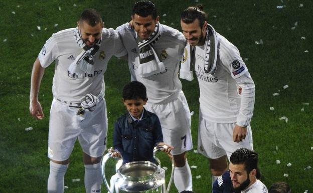 Karim Benzema, Cristiano Ronaldo y Gareth Bale posan junto al hijo del astro portugués con el trofeo de la Champions. 