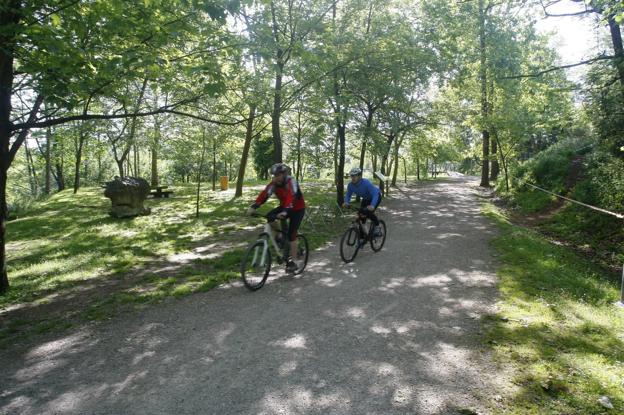 Dos ciclistas pasean por el parque de La Viesca, que ocupa terrenos de los municipios de Torrelavega y Cartes. :: LUIS PALOMEQUE