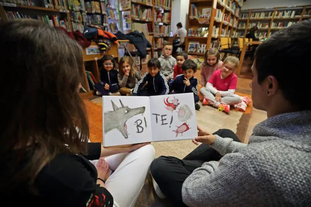 Dos alumnos del IES Valle del Saja cuentan un cuento en inglés a ocho niños y niñas en la biblioteca municipal. 