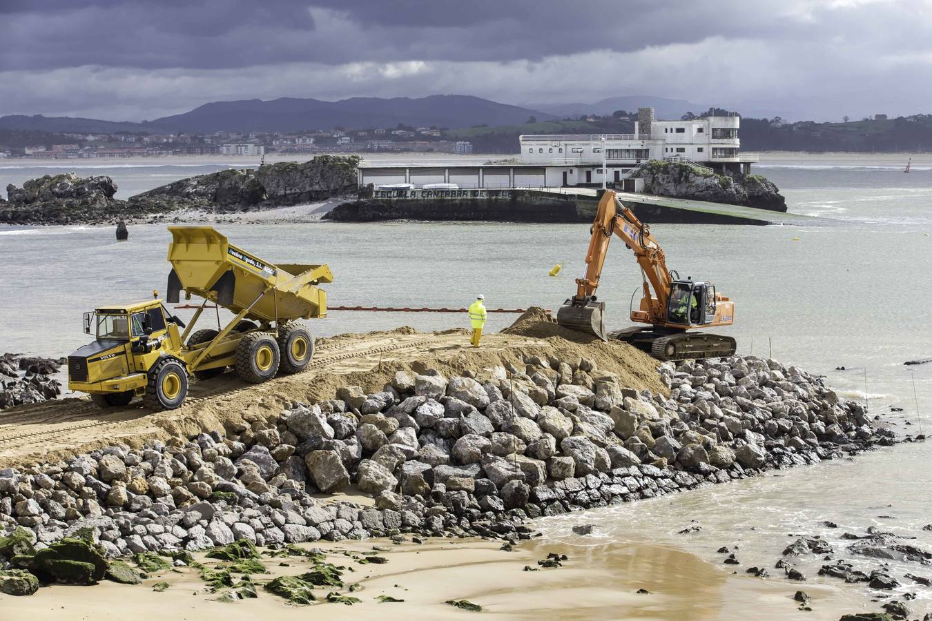 El primer dique para contener la arena ya asoma de forma evidente en La Magdalena.Con la playa cortada y la marea baja, la pala da forma al primero de los espigones, que llama la atención de los curiosos que se acercan a verlo 