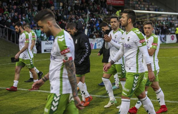 Los jugadores del Racing abandonan el terreno de juego en Lasesarre, con la grada detrás mostrando su malestar.