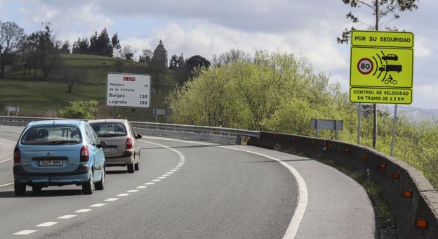 Dos vehículos pasan frente a la señal de tráfico que informa del radar de tramo que mide la velocidad, en Limpias. 