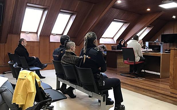 Uno de los acusados declara mientras el otro, escoltado por dos policías, escucha.