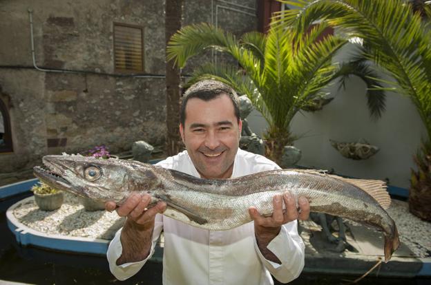 Toni González, chef del Nuevo Molino, en el jardín del histórico restaurante, con una merluza. 