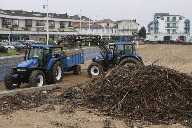 Las máquinas trabajan en la limpieza de la playa de La Ribera, en Suances.