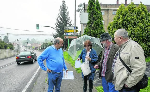 Algunos vecinos de Puente San Miguel, junto a la cámara del semáforo, portando copia de sus solicitudes y de sus multas.