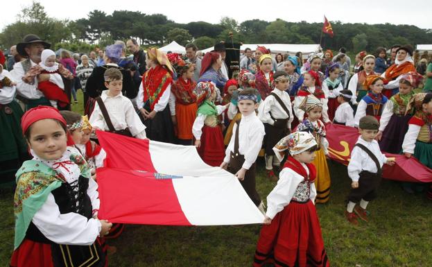 Los niños sostienen la bandera de Cantabria y el lábaro.