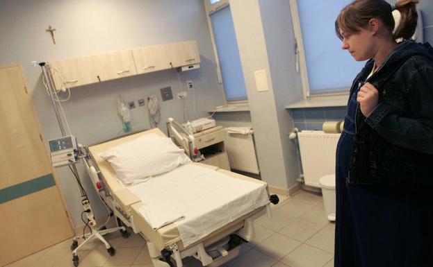 Una mujer embarazada se palpa el vientre mientras espera para dar a luz en un hospital. 