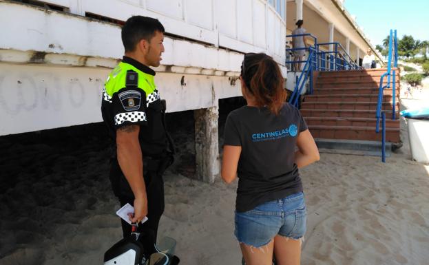 Un voluntario señala a un policía dónde se encuentran los vertidos.