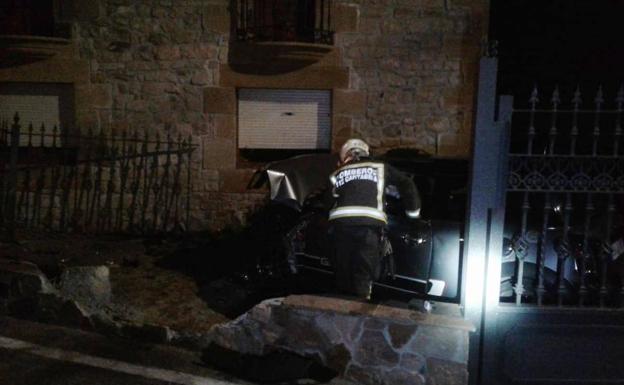 Un bombero, junto al coche empotrado contra la casa.