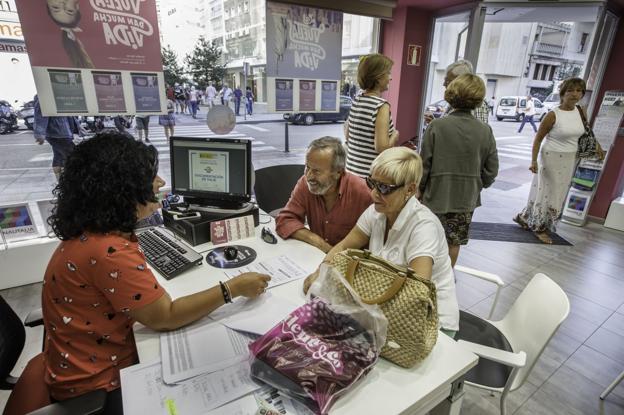 Varias personas reservan sus viajes con el programa Imserso en la agencia Nautalia, en Santander.