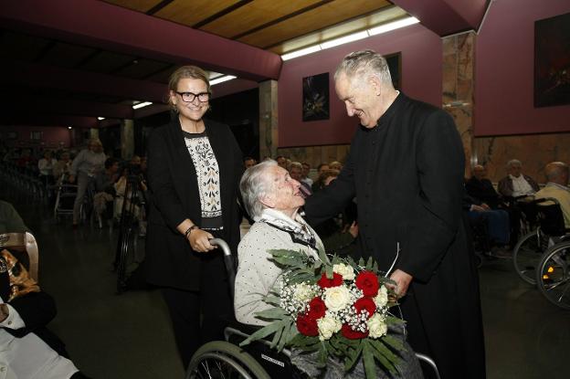 María López Fernández, de 101 años, recibe un ramo de flores de manos de López Ormazábal.
