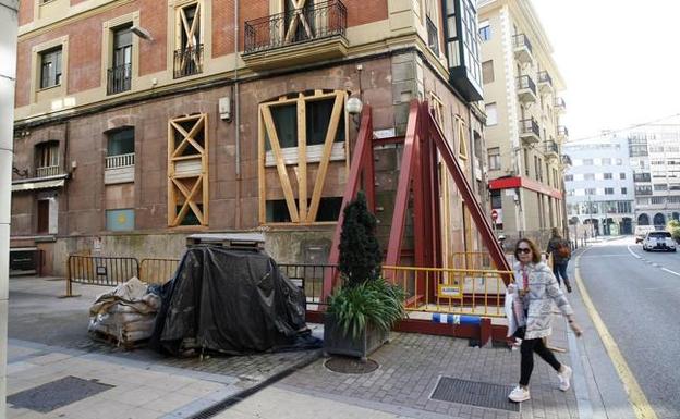 Una mujer camina junto a la esquina del edificio apuntalado.