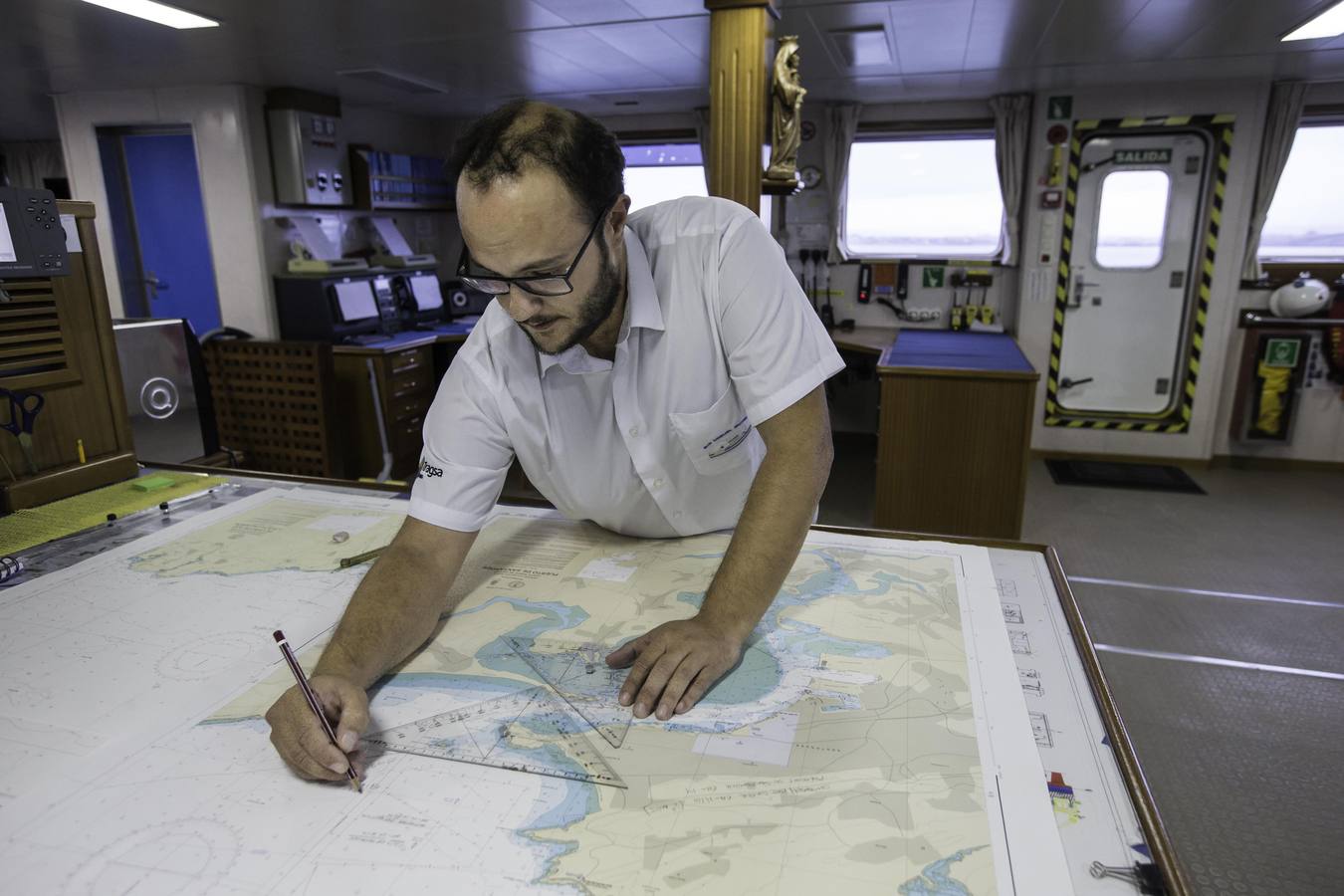 Uno de los tripulantes del barco traza en una carta de navegación.