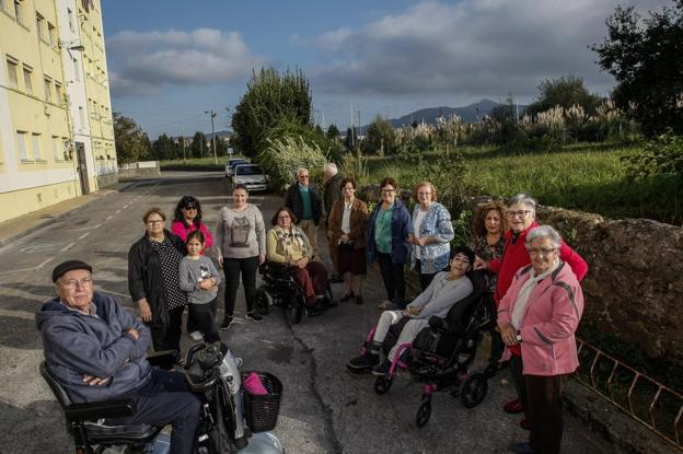 Vecinos del Barrio Covadonga posan junto a la finca «abandonada» y «llena de plumeros» que hay frente a sus viviendas.