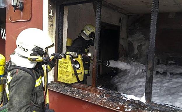 Los bomberos del parque de Laredo durante la extinción del fuego el domingo en la vivienda de Argoños. 