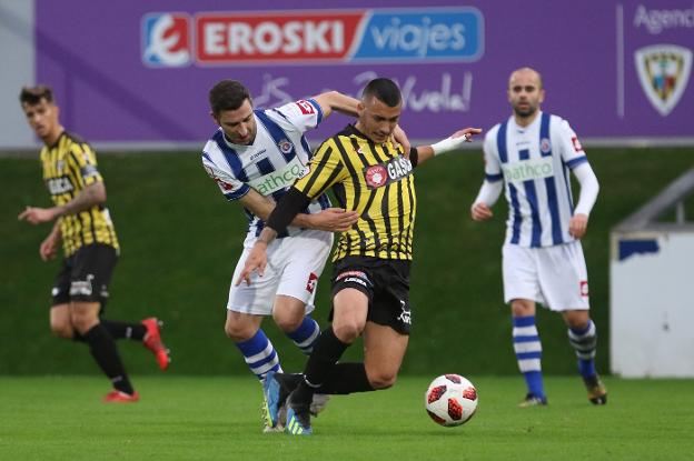 Nacho Rodríguez pugna con un rival del Barakaldo ante la mirada de Víctor.