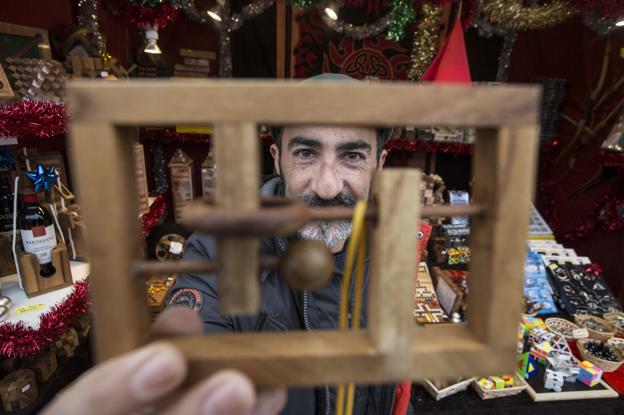 Adrián Fernández, comerciante en el mercado navideño de Santander, muestra uno de los juegos de ingenio