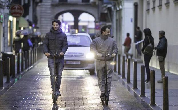 Jóvenes en patinete por el centro de Santander. 