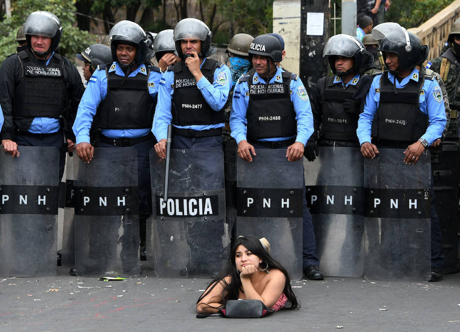Una seguidora del presidente de la oposición hondureña permanece tumbada ante miembros de la Policía en una protesta contra la reelección de Juan Orlando Hernández. 