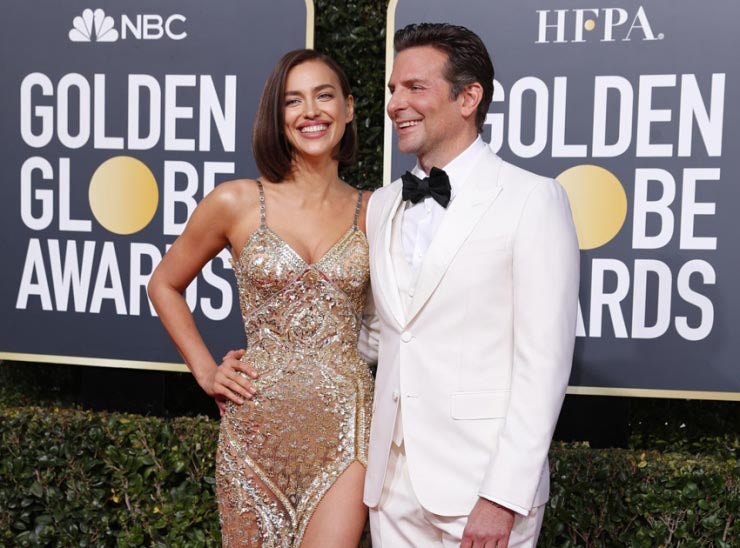 Irina Shayk optó por un vestido de tirantes en tonos dorados de Atelier Versace y su pareja, el actor Bradley Cooper, vistió un esmoquin blanco firmado por Gucci.