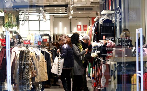 Varias mujeres observan las prendas rebajadas en una tienda de moda del centro. 
