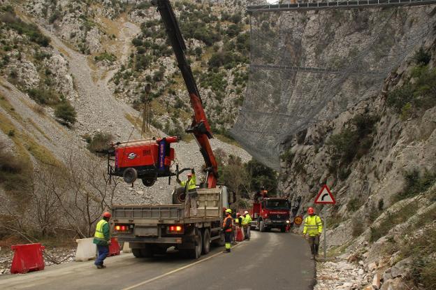 Un grupo de los pocos trabajadores que ayer quedaban sobre el terreno retira maquinaria con un camión grúa.