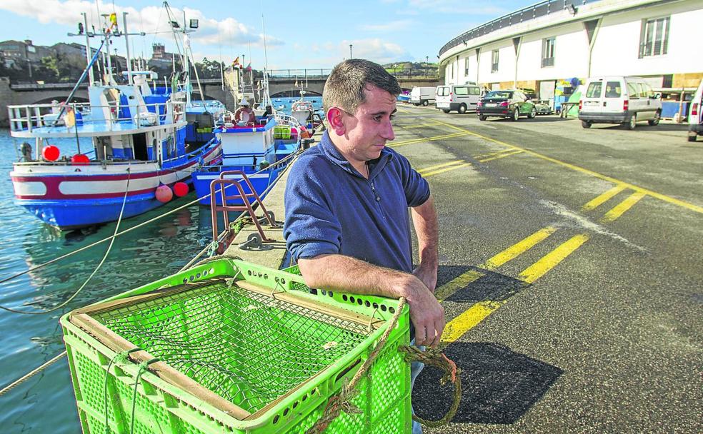 Óscar Bustamante, de 24 años, el socio más joven de la cofradía de San Vicente, posa ante el barco familiar con el que sale a faenar con su tío y su primo. 