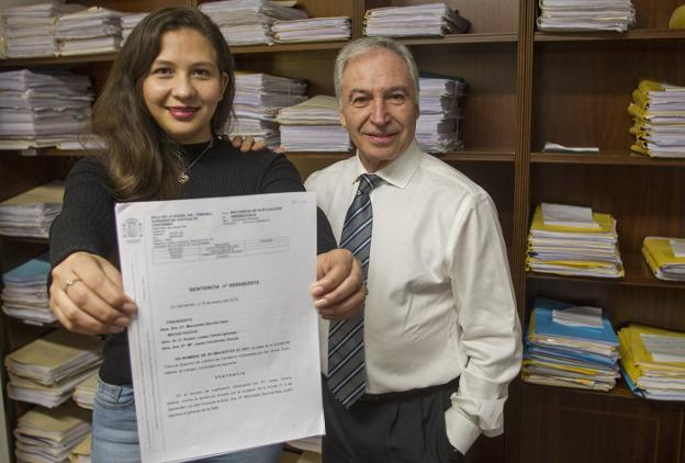 Leydy Bolívar y su abogado, Juan Manuel Ruiz, posan junto a la sentencia que declara nulo el despido de la joven.